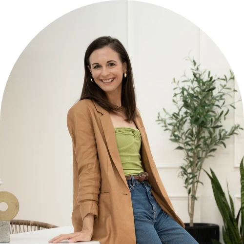 Kelsey Marsalona wearing a tan blazer, seated beside a plant